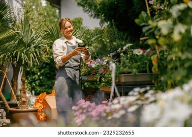 Female florist taking care of houseplant in flower shop. Plant care concept. High quality photo - Powered by Shutterstock