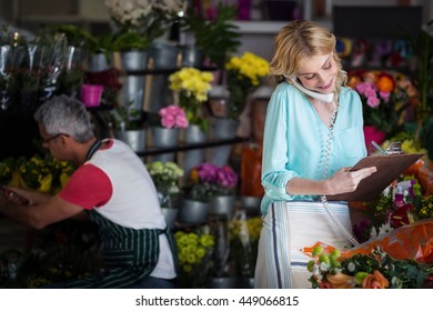 Female florist taking an order on telephone at the flower shop - Powered by Shutterstock