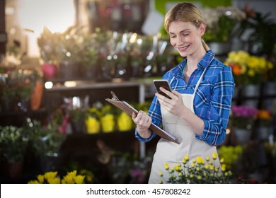 Female florist using mobile phone in the flower shop - Powered by Shutterstock