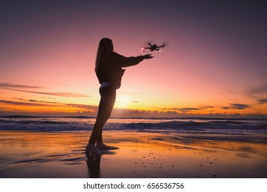 Female flying a drone at the beach as the sun rises