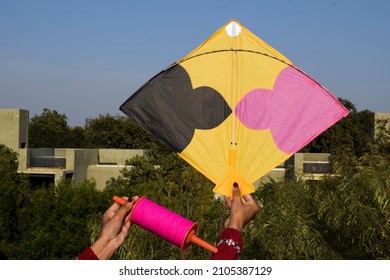 Female flying kite with sky background on occasion of Indian kite flying festival of Makar sankranti or Uttaryan, Pongal, Lohri celebration during day time on house terrace background. patang in hands