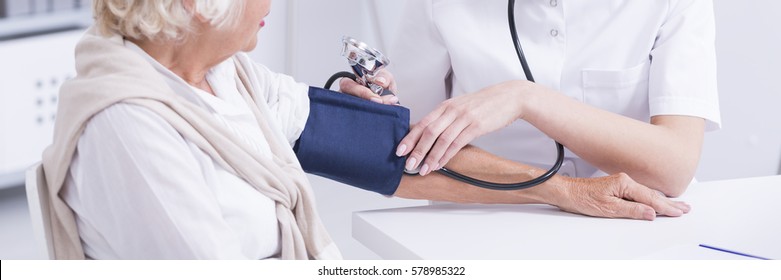 Female Focused Doctor Measuring Blood Pressure Of Her Older Patient