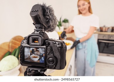 Female food blogger pouring oil onto potato while recording cooking video class on camera screen in kitchen, closeup - Powered by Shutterstock