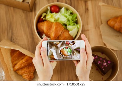 Female Food Blogger Reviewing Takeout Food, Taking Video On Phone. Italian Sub Sandwich, French Croissant W/ Salmon, Chocolate Cheesecake. Close Up, Top View, Pov, Copy Space, Wooden Table Background.