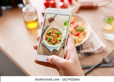 Female Food Photographer With Mobile Phone Taking Picture Of Pasta