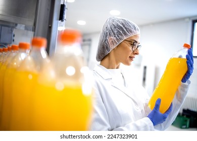 Female food technologist doing quality control of orange juice in bottling factory. - Powered by Shutterstock