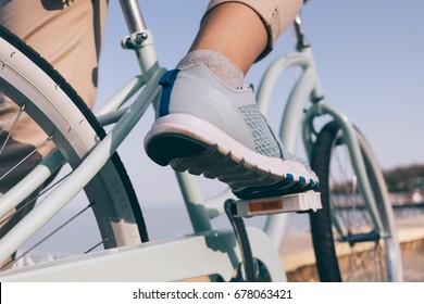 Female foot in a blue sneaker and a bicycle on the beach close-up - Powered by Shutterstock