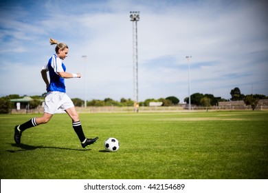 Female football player practicing soccer in a stadium - Powered by Shutterstock