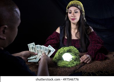 Female Fortune Teller Or Con Artist Swindling Money From A Male Customer Via Fraud.  The Man Is A Gullible Victim And The Psychic Is A Fraudulent Liar Swindling For Cash.