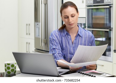 Female Freelance Worker Using Laptop In Kitchen At Home