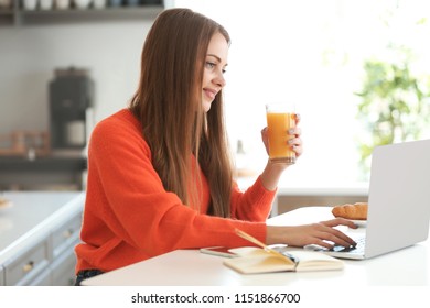 Female freelancer drinking juice while working on laptop at home - Powered by Shutterstock