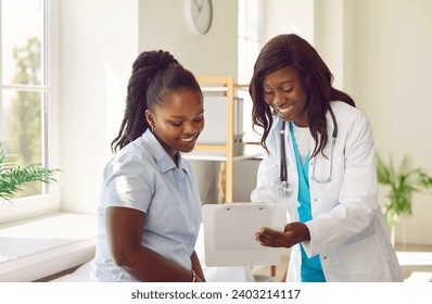 Female friendly doctor talking with a happy smiling african american woman patient sitting on the couch in office and looking to the report file with appointment during medical examination in clinic. - Powered by Shutterstock