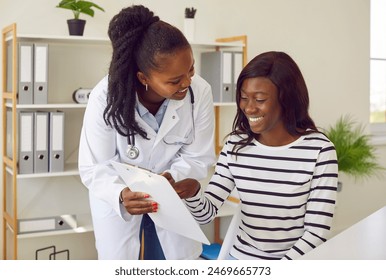 Female friendly doctor talking with a happy smiling african american woman patient sitting at the desk in office and looking to the report file with appointment during medical examination in clinic. - Powered by Shutterstock