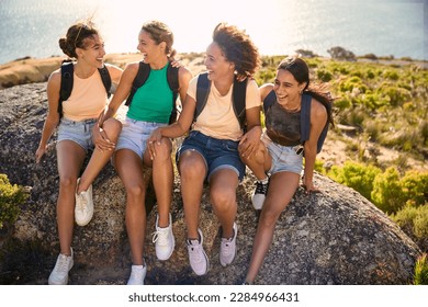 Female Friends With Backpacks On Vacation Taking A Break On Hike Through Countryside - Powered by Shutterstock