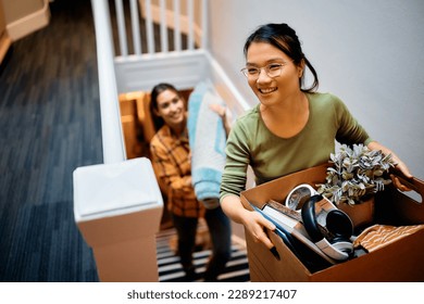 Female friends carrying their belongings into a new apartment. Focus is on Asian woman. - Powered by Shutterstock