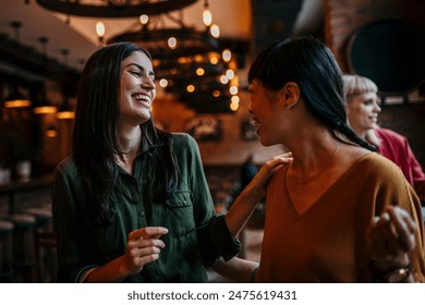 Female friends chatting and smiling, walking into a restaurant carrying shopping bags - Powered by Shutterstock