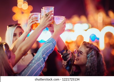 Female friends cheering with beer at music festival - Shutterstock ID 1221725134