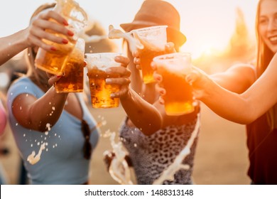 Female friends cheering with beer at music festival. splash