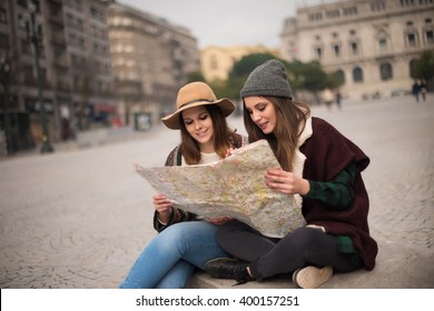 Female Friends Consulting A City Map In The Winter