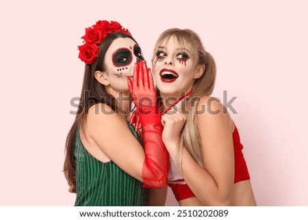 Female friends dressed for Halloween on pink background