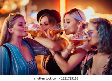 Female friends drinking beer at music festival