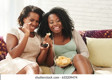 Female Friends Eating Potato Chips And Watching Tv Show