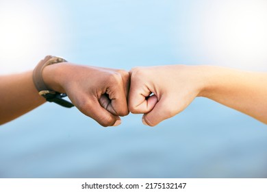 Female Friends Feeling Supported, United And Touching Fists At The Knuckles. Feeling Motivated And Ready To Achieve. Closeup Of Two Unknown People Giving Each Other A Fist Bump Against Blue Copyspac