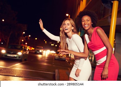 Female friends hailing taxi on city street at night - Powered by Shutterstock