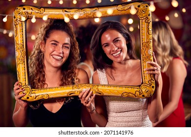 Female Friends Having Fun Posing With Photo Booth Photo Frame At Party In Bar - Powered by Shutterstock