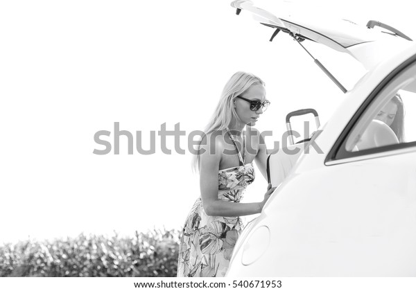 Female friends loading luggage in car trunk against\
clear sky