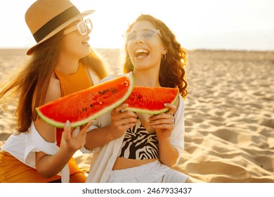 Female friends on vacation at the beach in summer eating a watermelon with the sea in the background, sitting on the sand at sunset. People, lifestyle, travel, nature and vacations concept. - Powered by Shutterstock