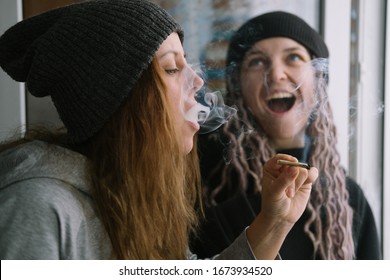 Female Friends Wearing Hats And Rasta Dreadlocks Hair Style Smoking Self-roll Weed Cigarette