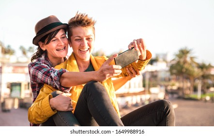 Female Friendship Concept With Girls Couple Taking Selfie Outdoors In Tenerife - Lgbtq Genuine Love Relationship With Happy Millennial Girlfriends Having Fun - Happy Playful Women On Warm Filter