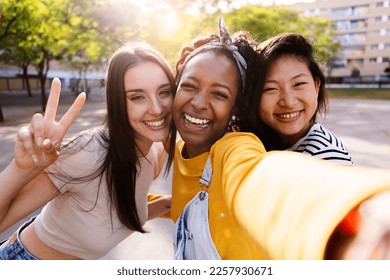 Female friendship concept with three diverse young women taking selfie outdoor. Happy millennial ladies having fun together on summer vacation. - Powered by Shutterstock