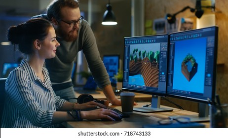 Female Game Developer Has Discussion with Male Project Manager While Working on a Game Level on Her Personal Computer with Two Displays. They Work in a Modern Loft Office Creative Environment.