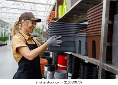 Female Garden Shop Worker Takes Many Flower Pots From A Shelf