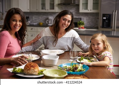 Female Gay Couple And Daughter Dining At Home Look To Camera