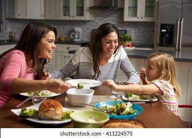 Female gay couple and daughter having dinner in their kitchen