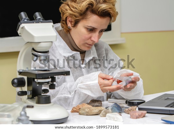 Female geologist researcher analysing a rock\
at her workplace.
