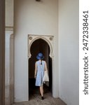 A female girl woman tourist in a summer dress walking through an ornate islamic moorish architecture door in the Alcazaba fortress in Malaga