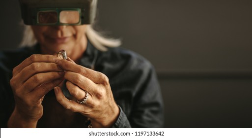 Female goldsmith inspecting jewelry using magnifying glass in workshop.  Woman jeweler inspecting diamond ring with magnifying glass. - Powered by Shutterstock