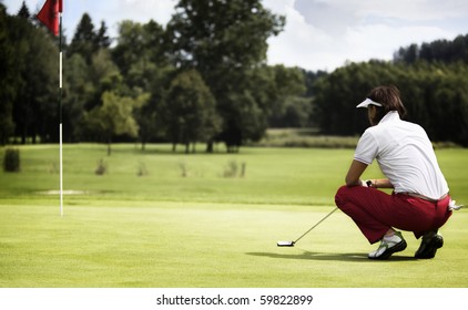 Female golf player with putter squatting to analyze the green at golf course. - Powered by Shutterstock