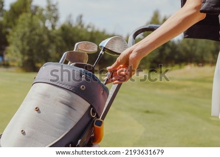 Female golf player taking golf club from bag on a summer day.