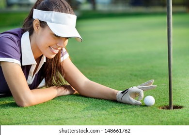 Female Golfer Pushing Ball In Hole, Sporting Cheat