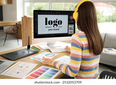 Female graphic designer in headphones working with computer at office, back view - Powered by Shutterstock