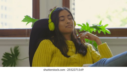 Female graphic designer listening music on headphones in office - Powered by Shutterstock