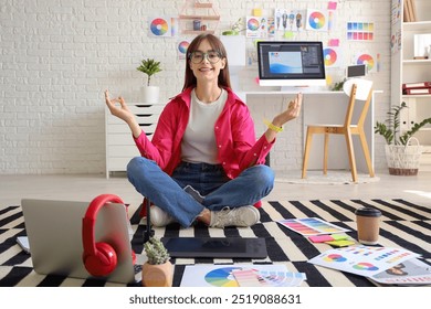 Female graphic designer meditating on floor in office - Powered by Shutterstock