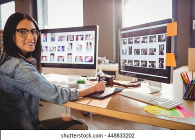 Female Graphic Designer Using Graphic Tablet While Working On Computer At Office