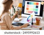 Female graphic designer working with color palette at table in office