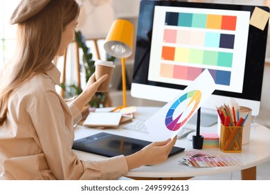 Female graphic designer working with color palette at table in office